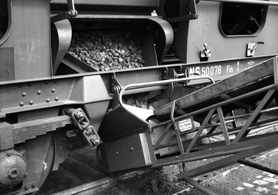 849050 Afbeelding van het overladen van steenkool uit een zelflosser op de laad- en losplaats van het N.S.-station ...